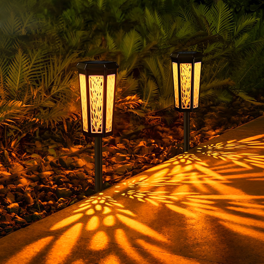 Solar stake light casting colorful leaf shadows on a paved pathway, enhancing nighttime garden aesthetics.