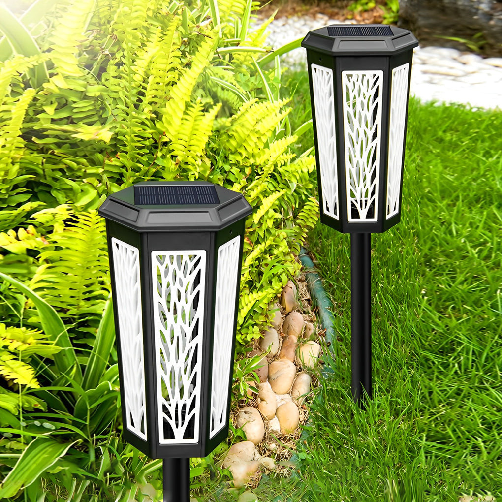 Solar stake light casting intricate leaf shadows on a garden bed, adding charm to the outdoor space.