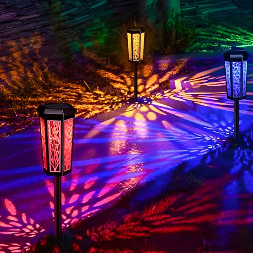 Solar stake light illuminating a garden with vibrant red and green leaf patterns on the ground.