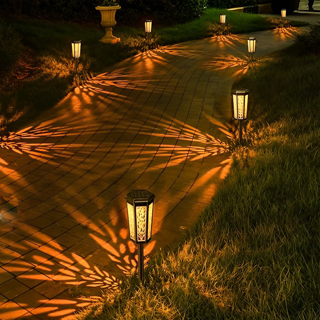 Solar stake light illuminating a garden path with warm leaf patterns, creating a cozy outdoor atmosphere.