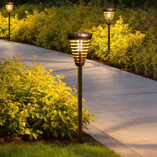 Solar torch light with a flame design, illuminating a garden pathway at night.