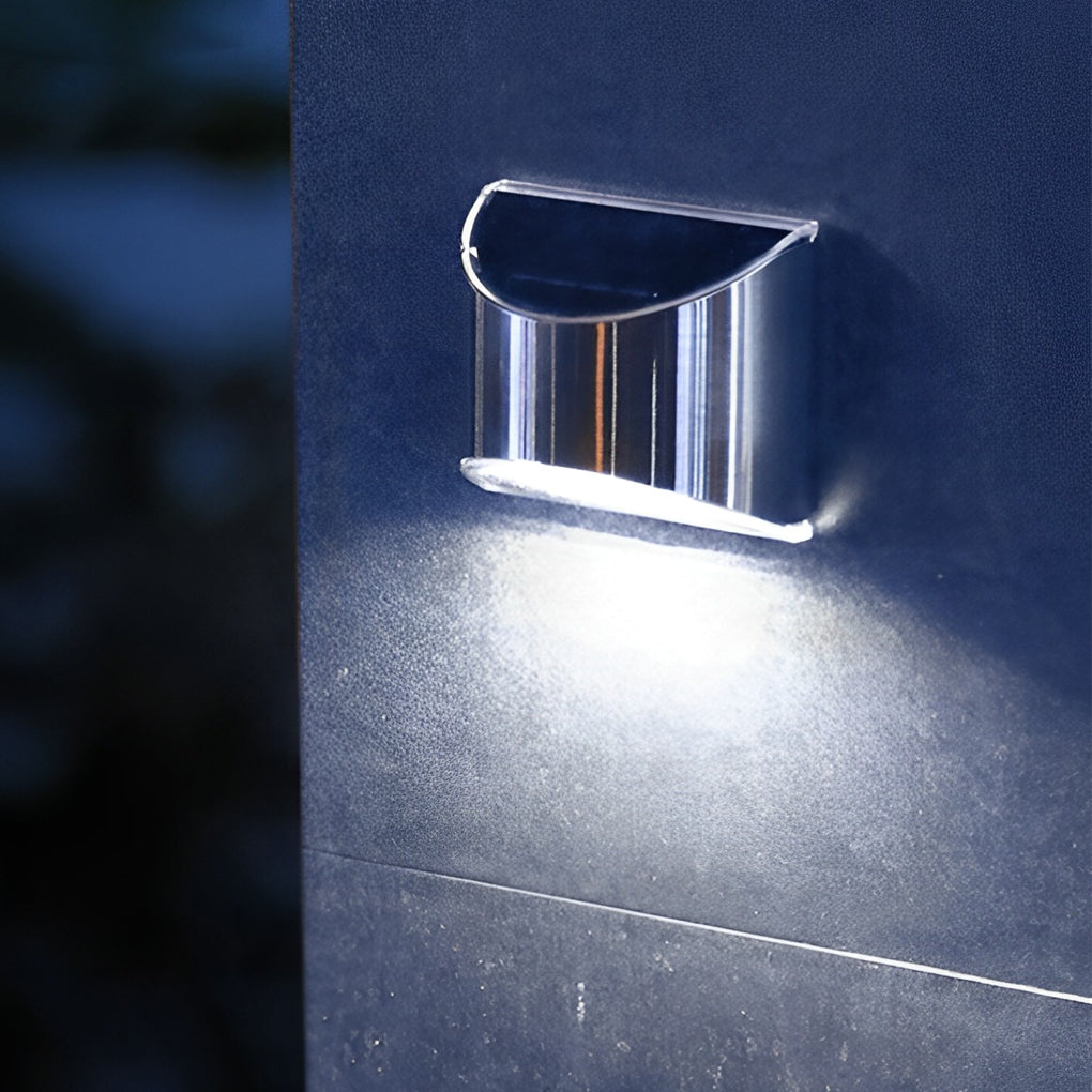 Stainless steel wall lamp with a rectangular design, emitting bright light on an exterior wall.