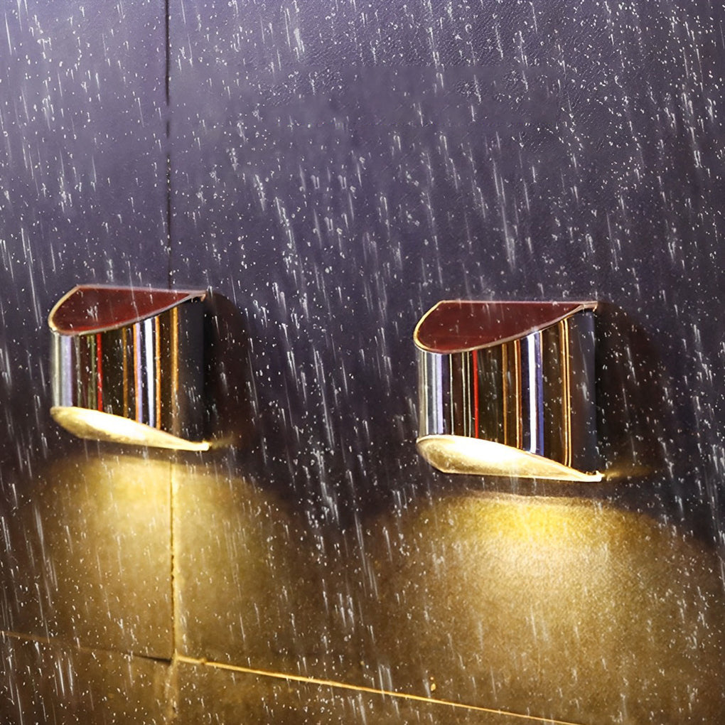 Stainless steel wall lamp with a solar panel, mounted on a wall under clear blue sky.