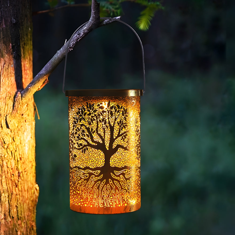 Tree of life lantern hanging from a tree branch, casting a cozy glow.